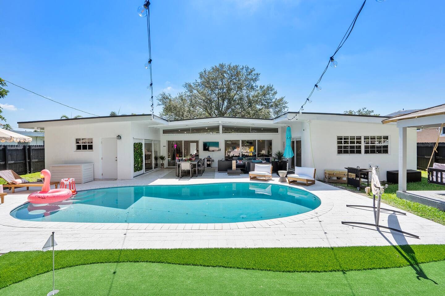 Sunny daytime view of backyard pool and putting green