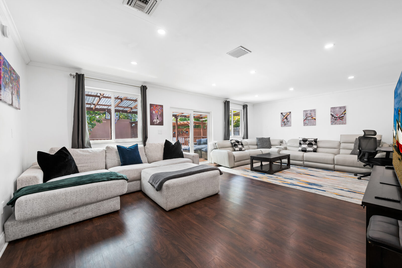 Large living room with dark wood floor and two gray sectionals